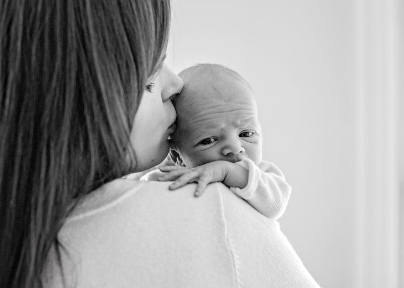 Family Photographer, a mother holds her newborn baby to her shoulder